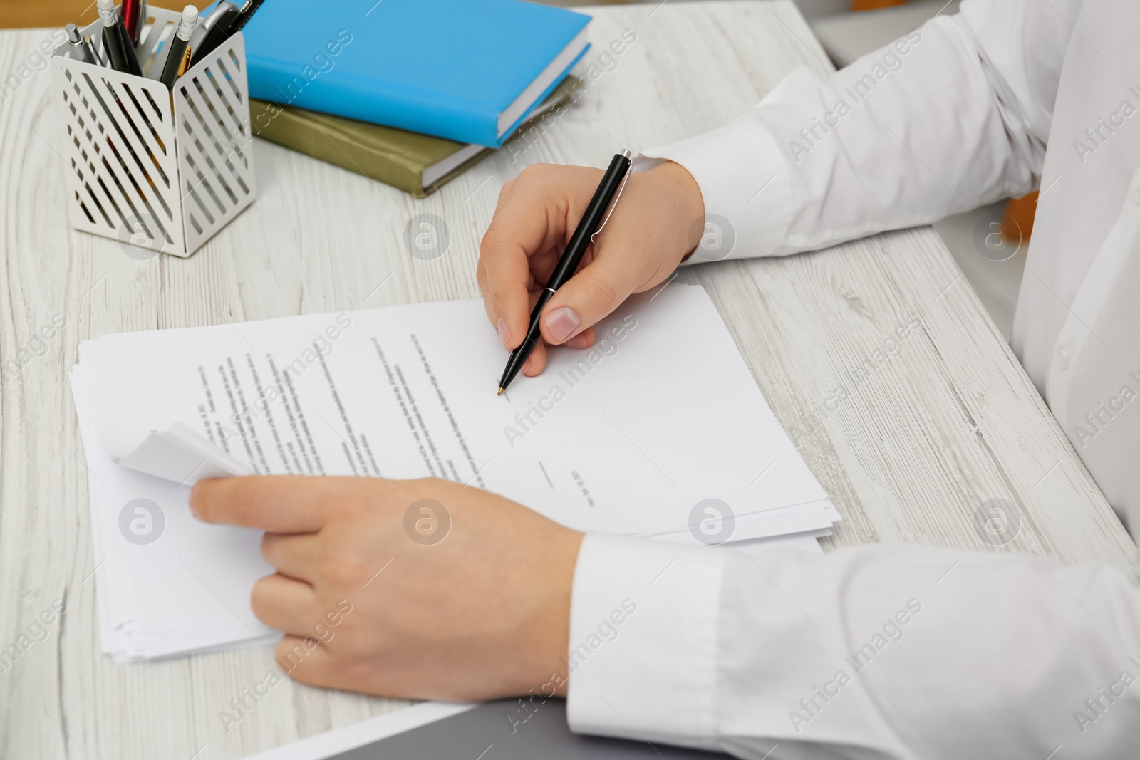 Photo of Man signing document at wooden table, closeup