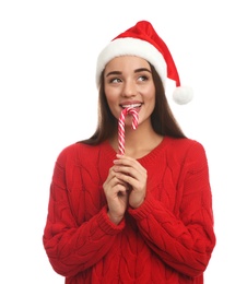 Photo of Young woman in red sweater and Santa hat eating candy cane on white background. Celebrating Christmas