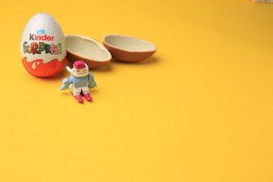 Photo of Sveti Vlas, Bulgaria - June 29, 2023: Kinder Surprise Eggs and toy on orange background, space for text