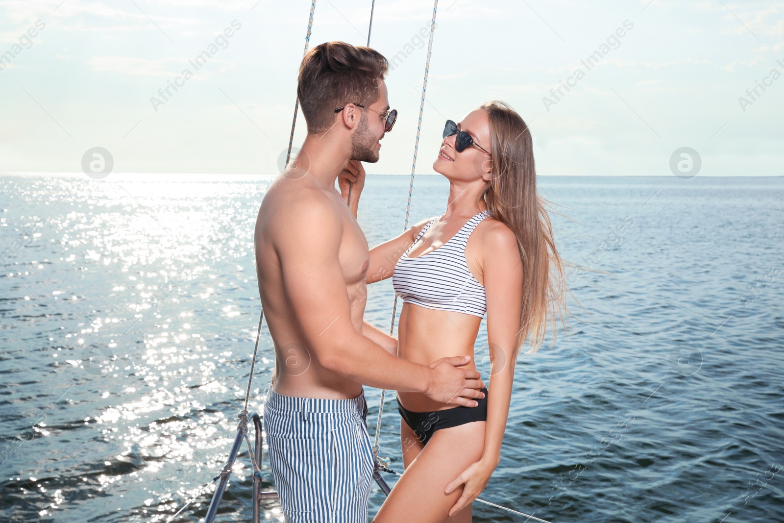 Photo of Young man and his beautiful girlfriend in bikini on yacht. Happy couple on vacation