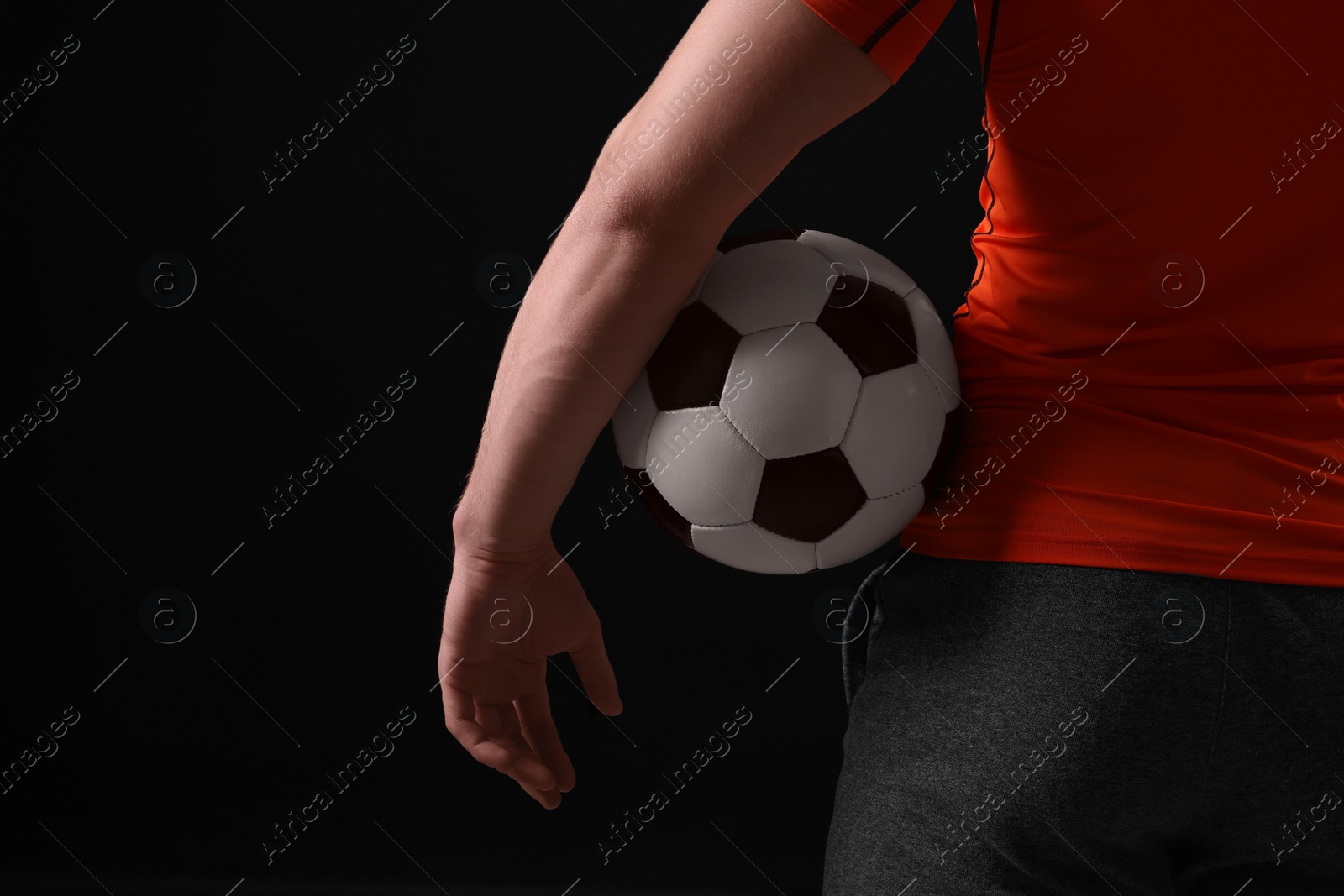 Photo of Athletic man with soccer ball on black background, closeup. Space for text
