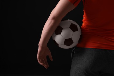 Photo of Athletic man with soccer ball on black background, closeup. Space for text