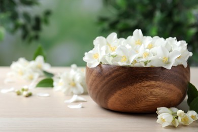 Bowl with beautiful jasmine flowers on white wooden table, closeup. Space for text