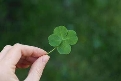 Photo of Woman holding one beautiful green clover leaf outdoors, closeup