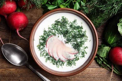 Photo of Delicious cold summer soup with kefir served on wooden table, flat lay