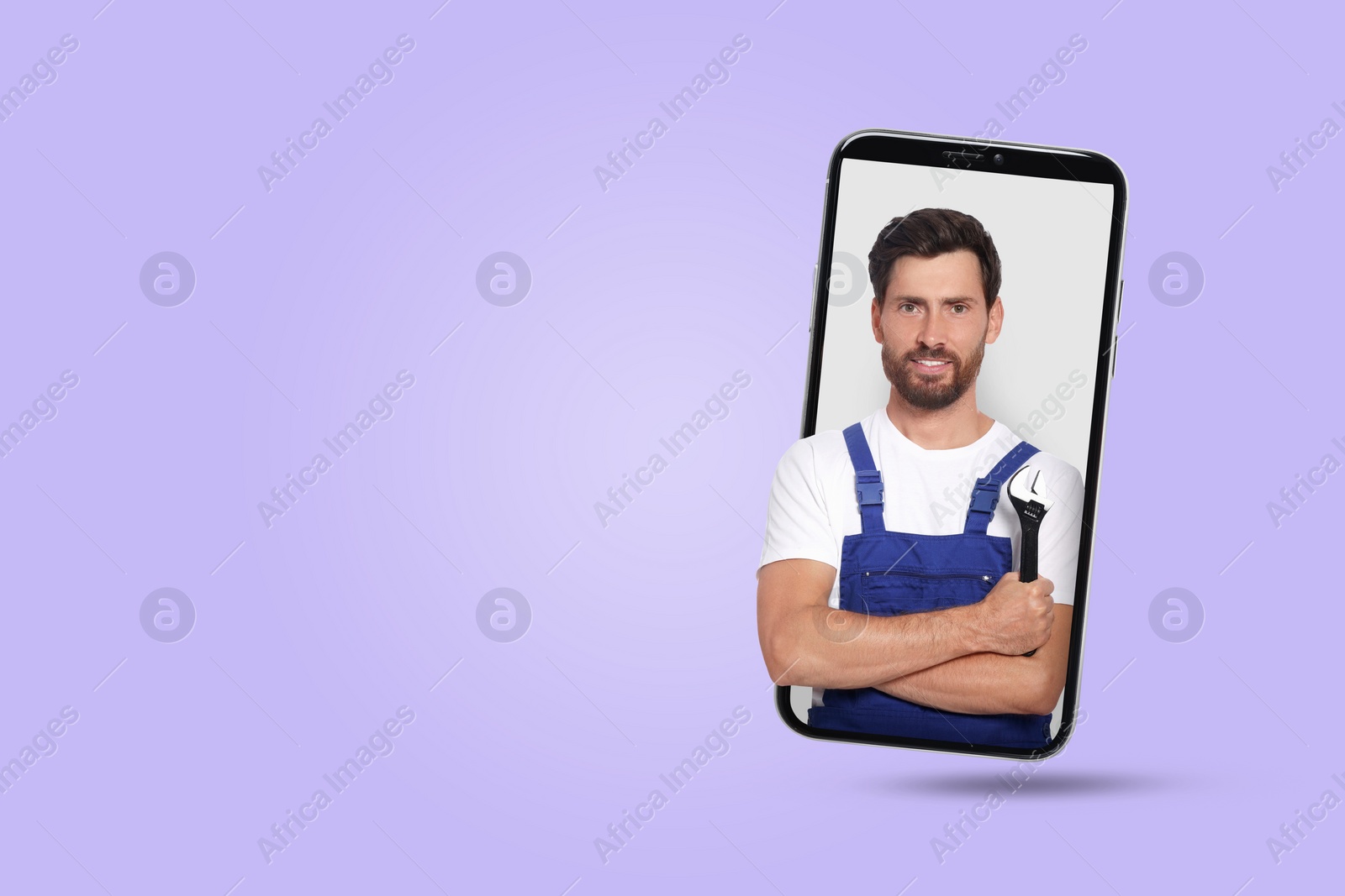 Image of Plumber looking out of smartphone on light violet background. Space for text