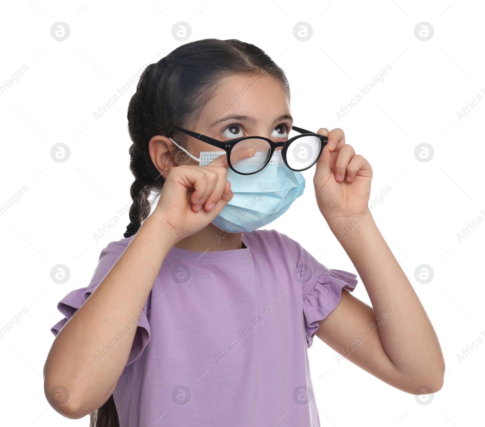 Photo of Little girl wiping foggy glasses caused by wearing medical face mask on white background. Protective measure during coronavirus pandemic