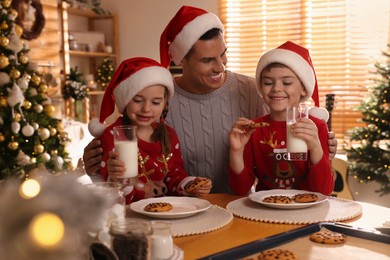 Photo of Happy father and his children eating delicious Christmas cookies at home