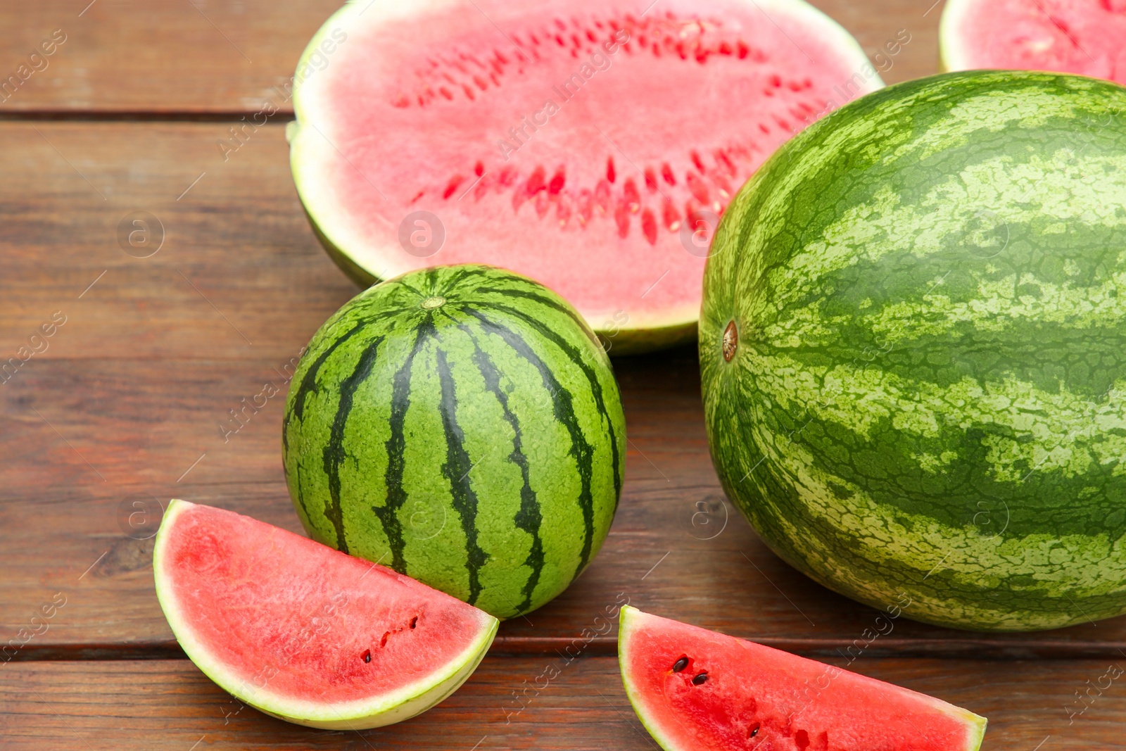 Photo of Delicious whole and cut watermelons on wooden table