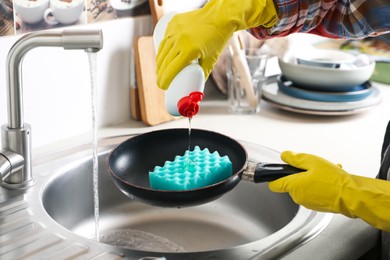 Photo of Woman using cleaning product for washing frying pan in sink indoors, closeup