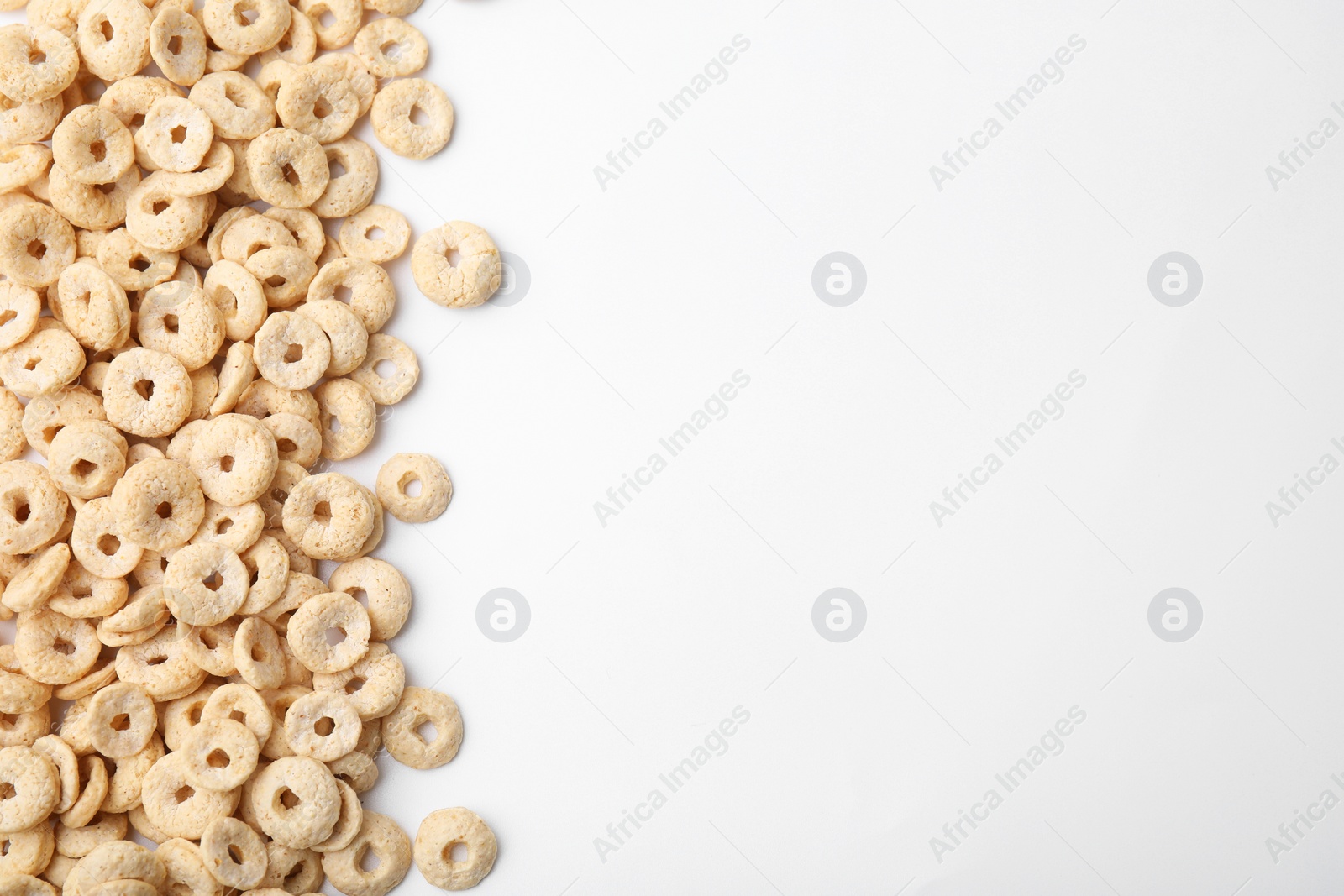 Photo of Tasty cereal rings on white background, flat lay. Space for text