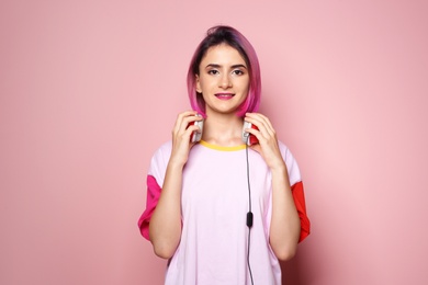 Photo of Young woman with trendy hairstyle and headphones against color background