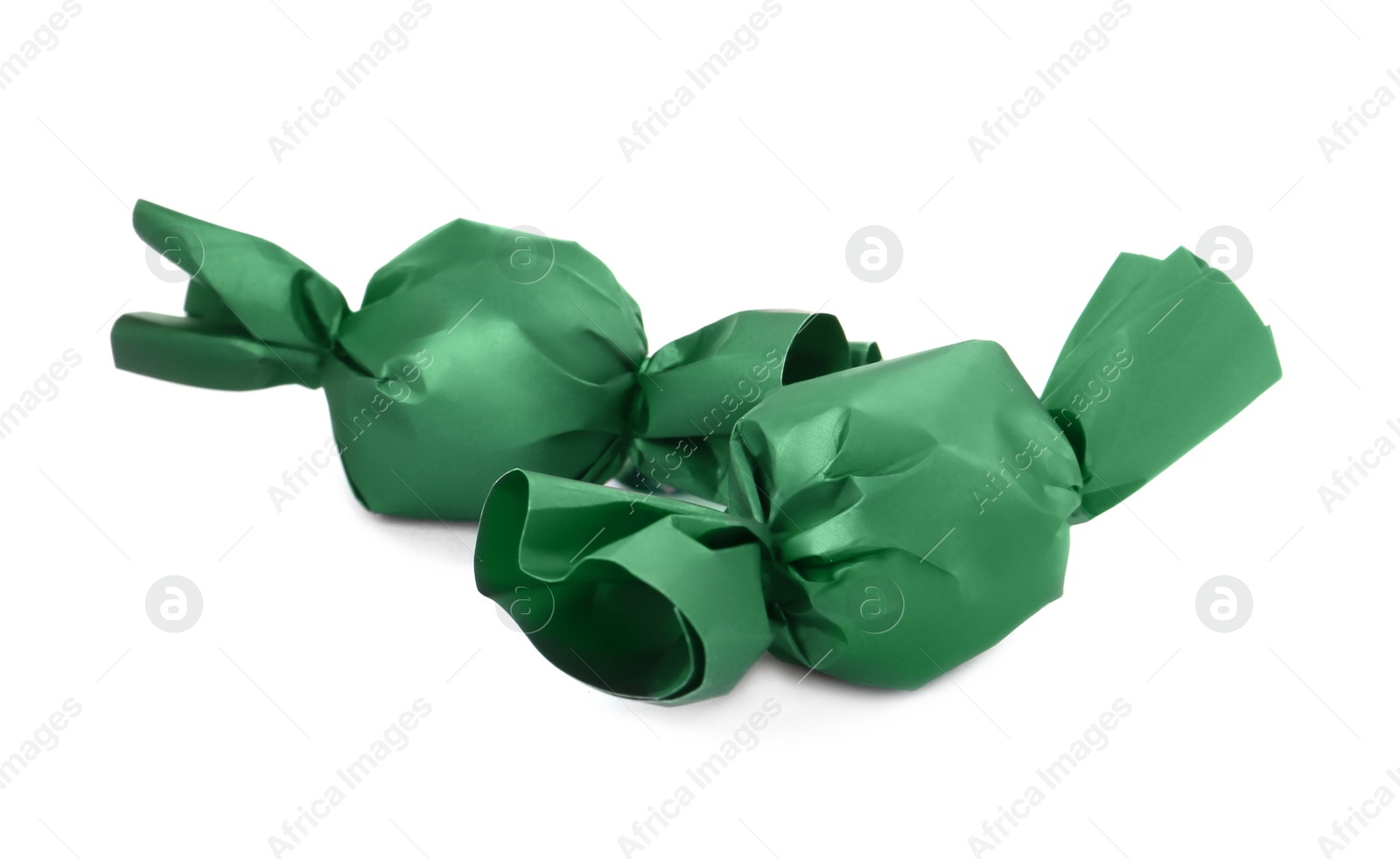 Photo of Delicious candies in dark green wrappers isolated on white