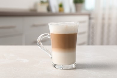 Photo of Glass cup of delicious layered coffee on light marble table indoors