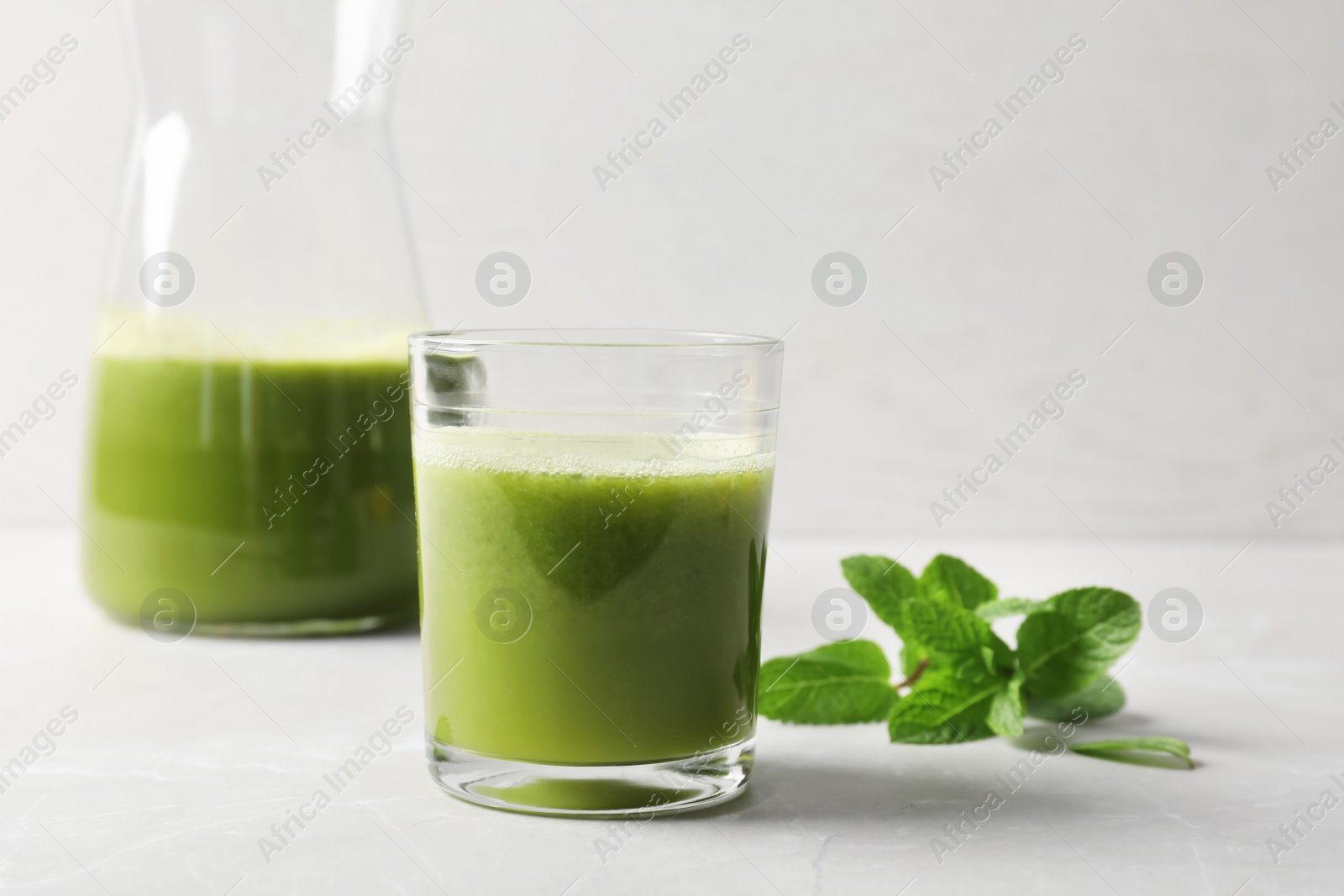 Photo of Glassware with delicious detox juice and mint on table