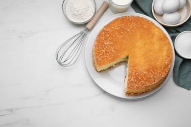 Tasty sponge cake, whisk and ingredients on white marble table, flat lay. Space for text