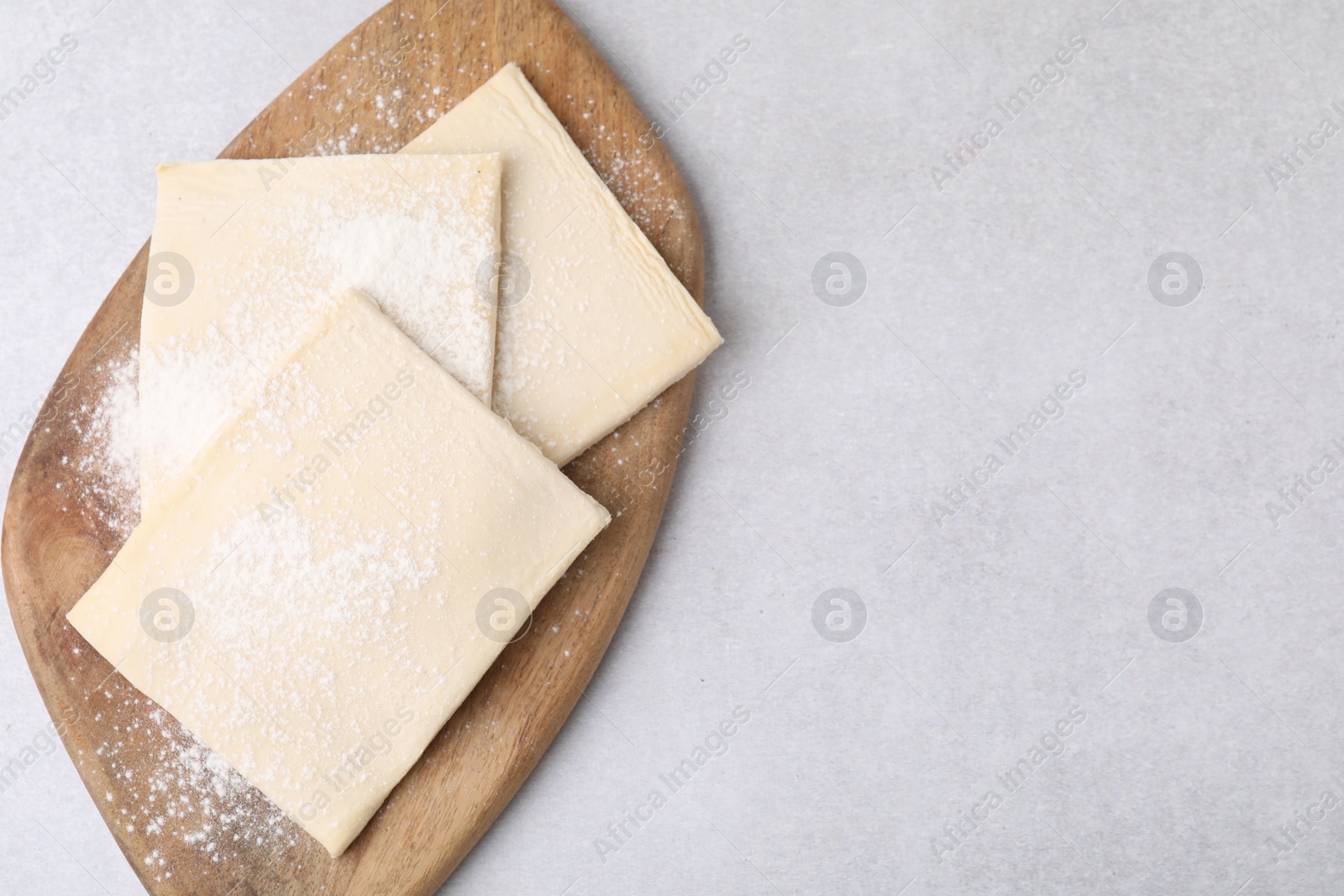 Photo of Raw puff pastry dough on white table, top view. Space for text