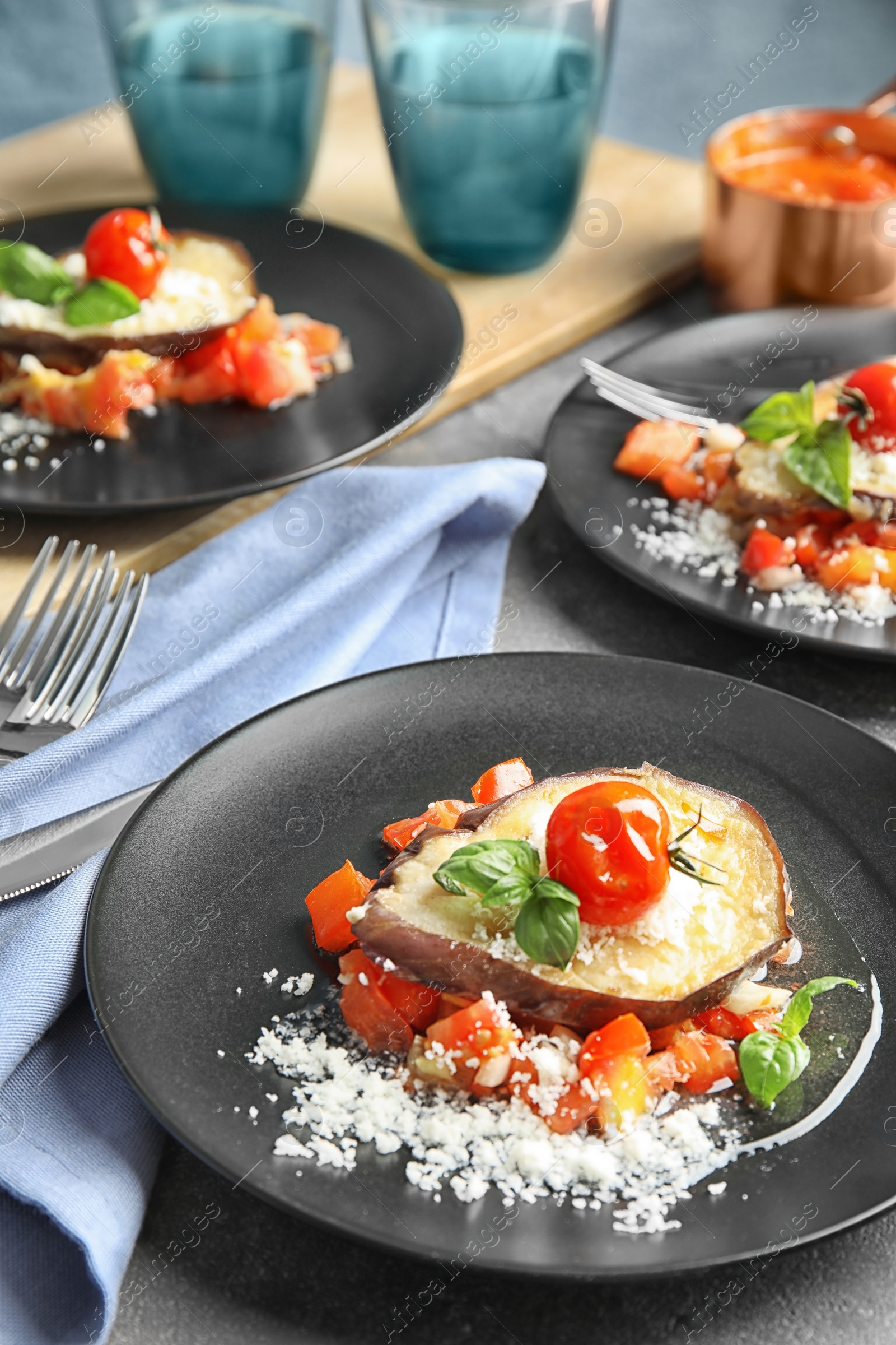 Photo of Baked eggplant with tomatoes, cheese and basil served on table