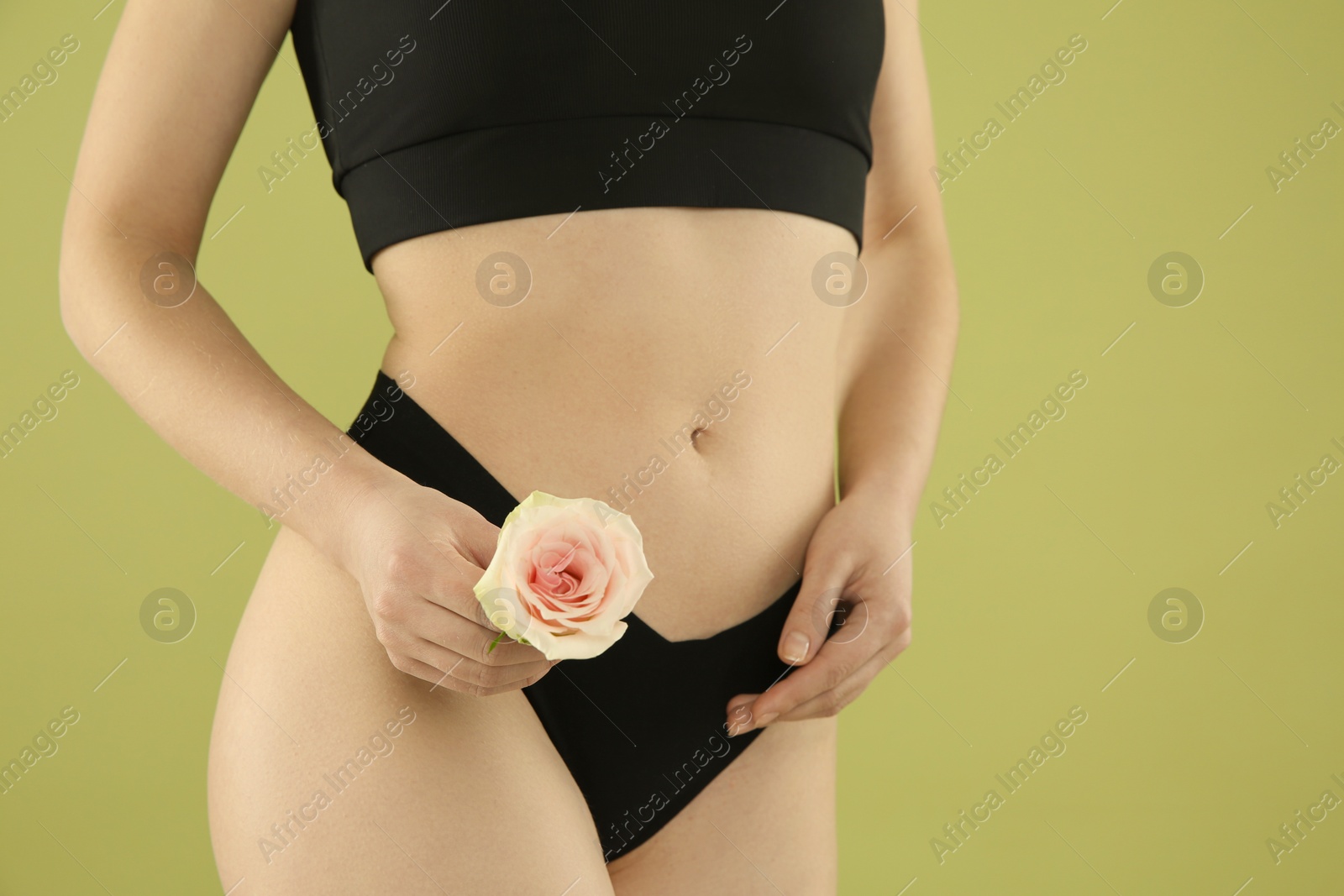 Photo of Gynecology. Woman in underwear with rose flower on green background, closeup