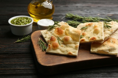 Photo of Delicious focaccia bread on black wooden table, closeup