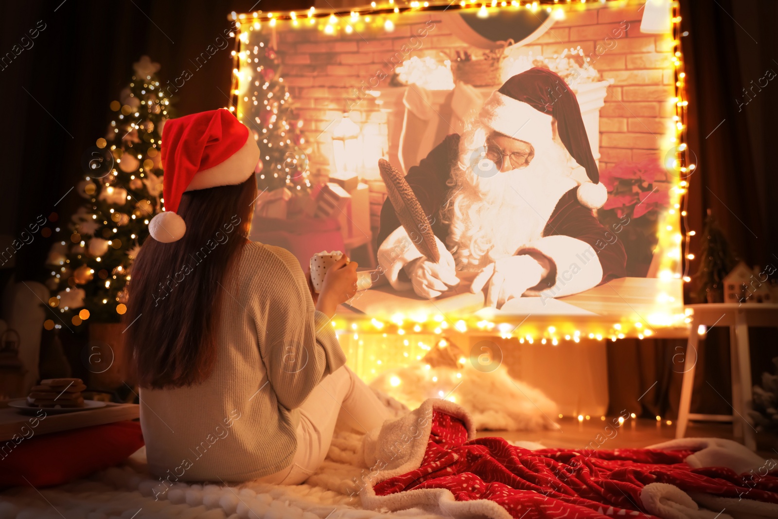 Image of Woman watching Christmas movie via video projector in room. Cozy winter holidays atmosphere