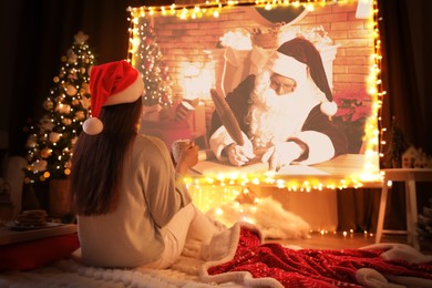 Image of Woman watching Christmas movie via video projector in room. Cozy winter holidays atmosphere