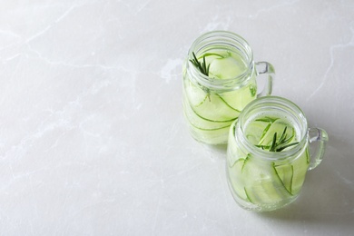 Photo of Mason jars of fresh cucumber water on grey background. Space for text