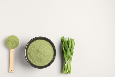 Photo of Wheat grass powder and fresh green sprouts on light table, flat lay. Space for text