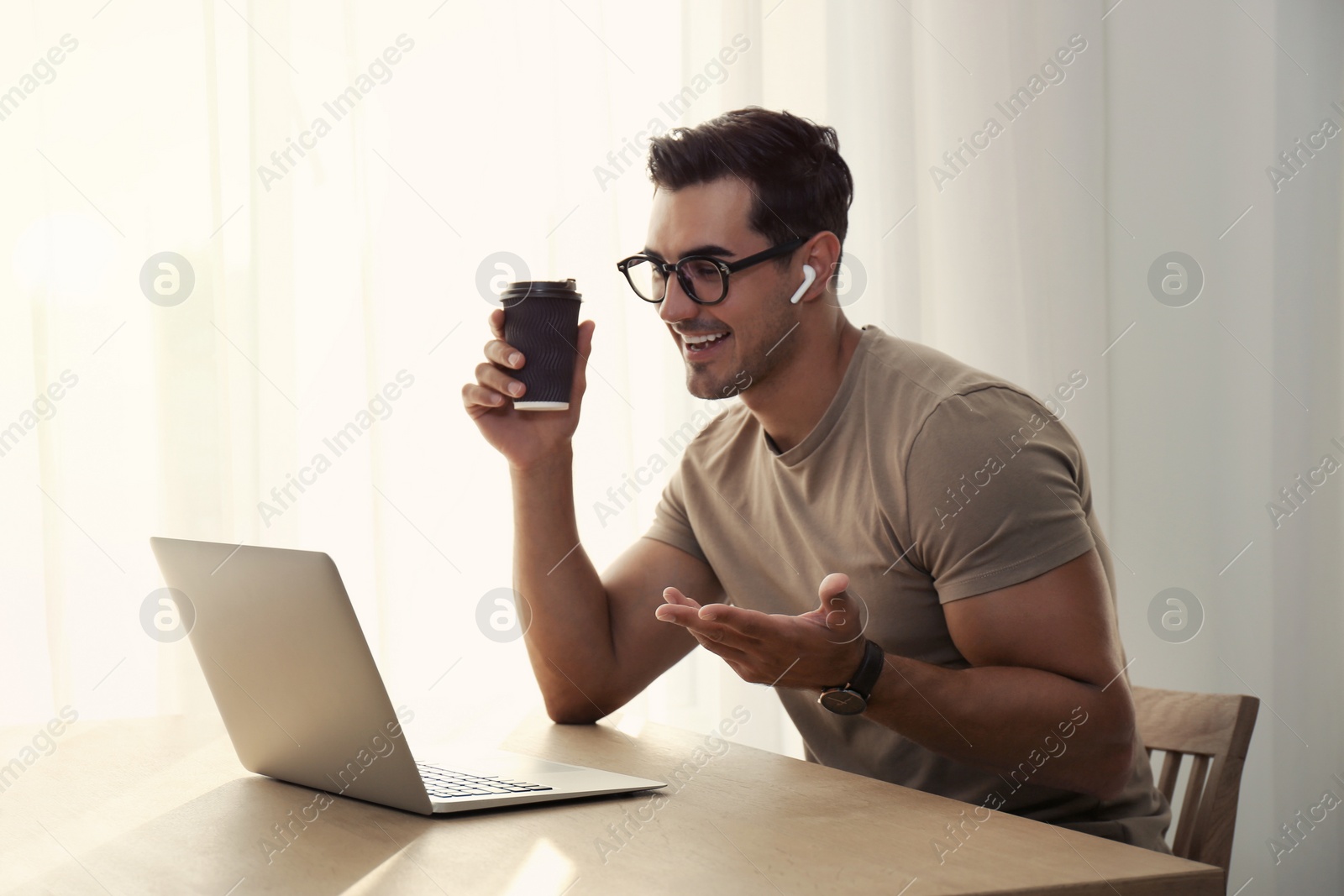 Photo of Portrait of young man with laptop at table indoors