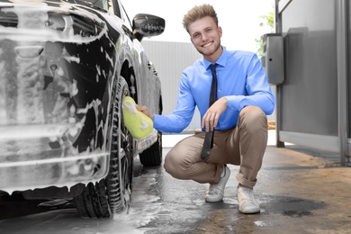 Businessman cleaning auto with sponge at self-service car wash