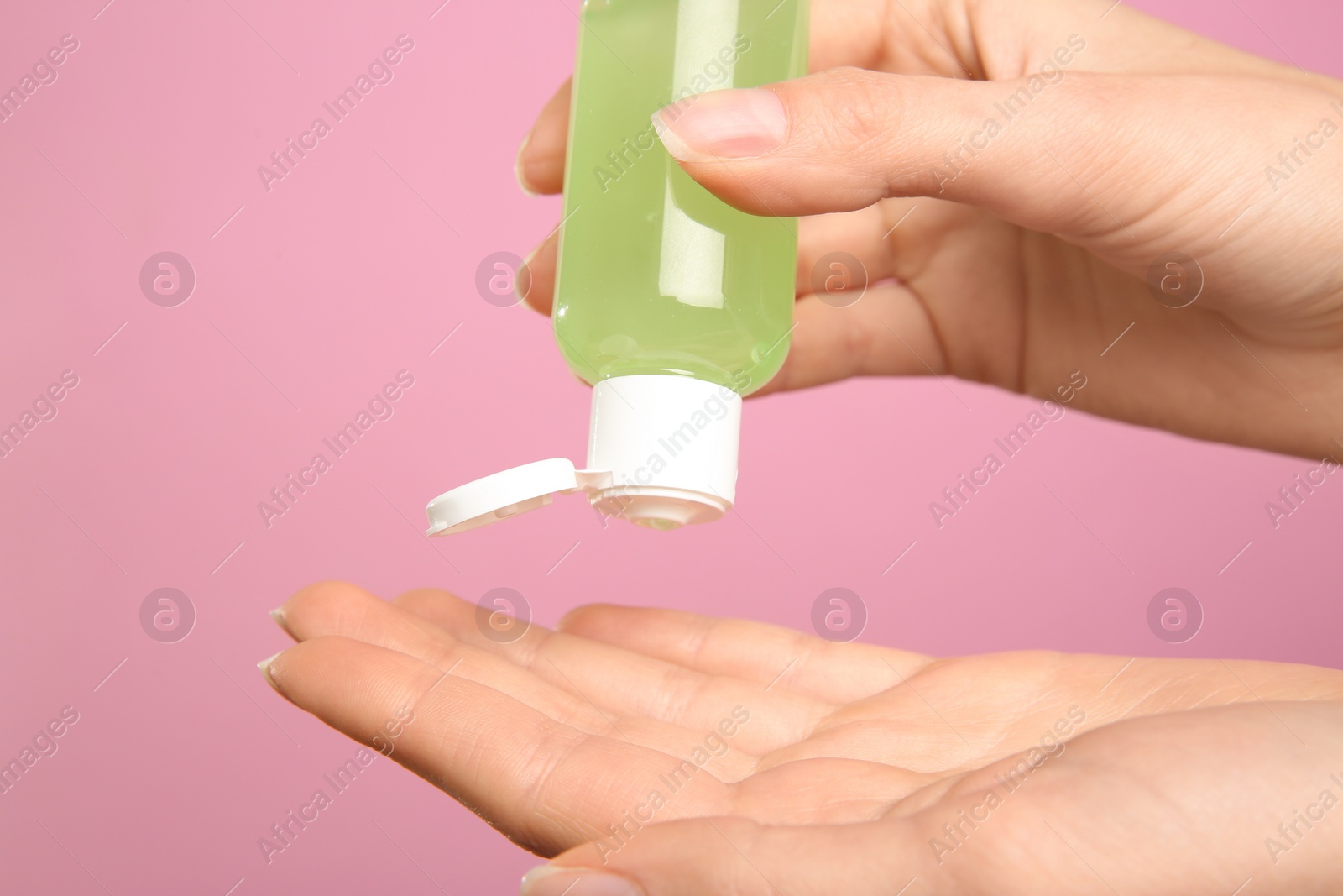 Photo of Woman applying antiseptic gel on pink background, closeup