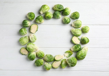 Frame made with fresh Brussels sprouts on white wooden table, flat lay. Space for text