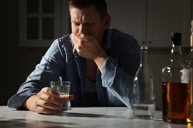 Photo of Addicted drunk man with alcoholic drink at table in kitchen