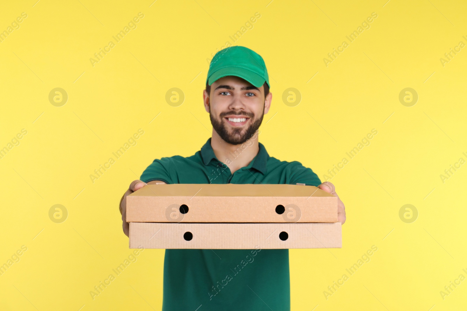 Photo of Young courier with pizza boxes on color background. Food delivery service