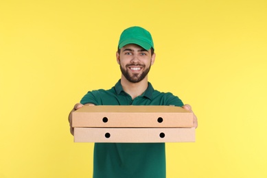 Young courier with pizza boxes on color background. Food delivery service