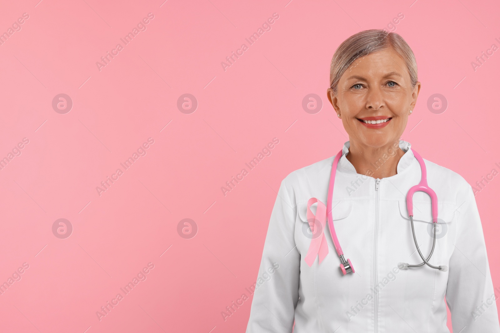 Photo of Doctor with pink ribbon and stethoscope on color background, space for text. Breast cancer awareness