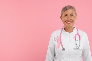 Doctor with pink ribbon and stethoscope on color background, space for text. Breast cancer awareness