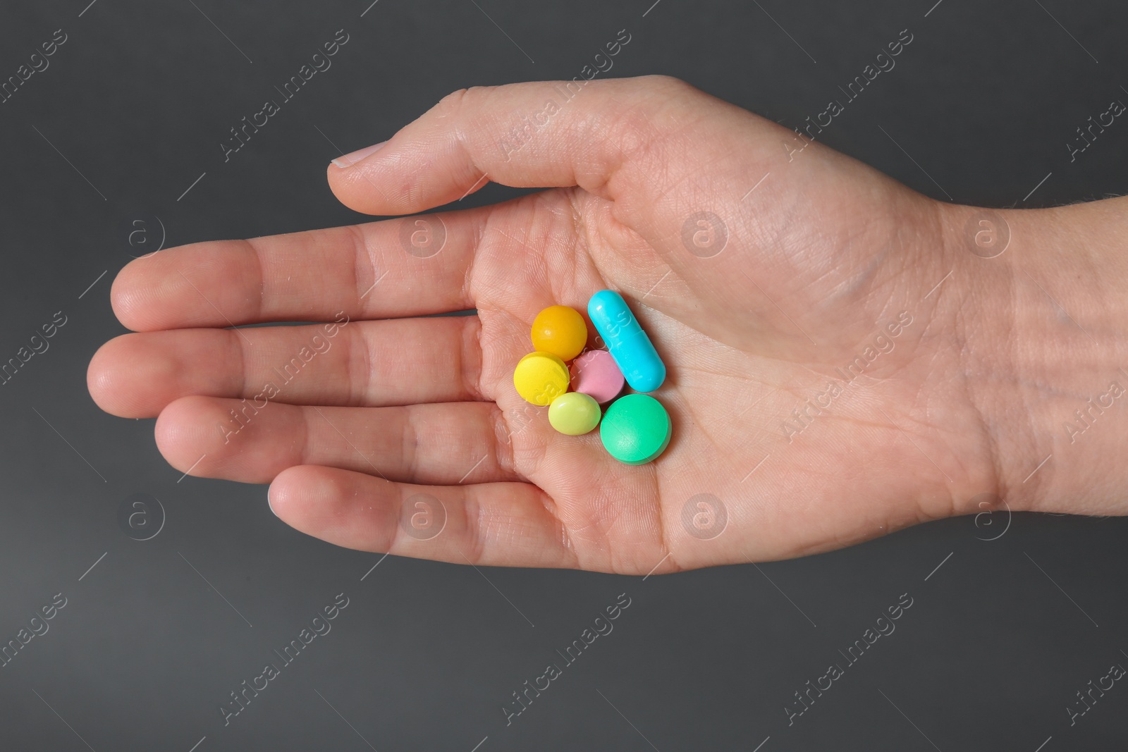 Photo of Woman holding weight loss pills on gray background, closeup