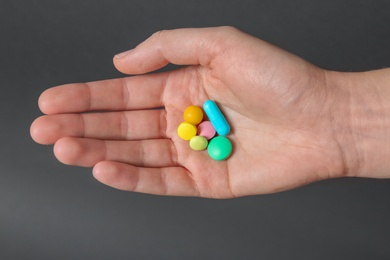 Photo of Woman holding weight loss pills on gray background, closeup