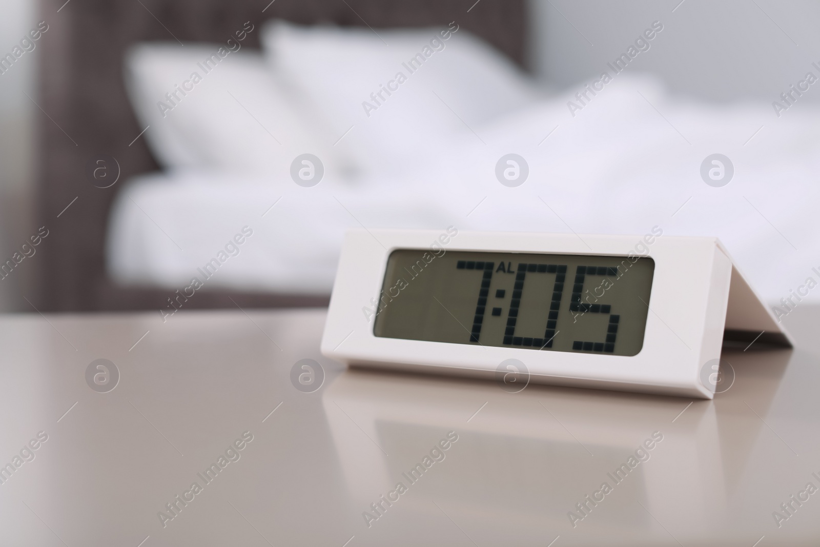 Photo of Digital alarm clock on table in bedroom. Time to wake up