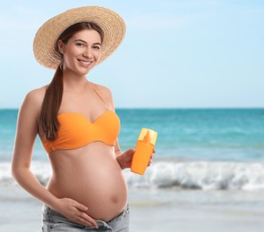 Image of Young pregnant woman with sun protection cream on beach