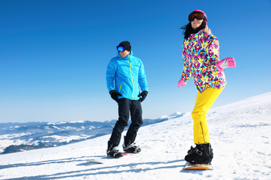 Photo of Couple snowboarding on snowy hill. Winter vacation