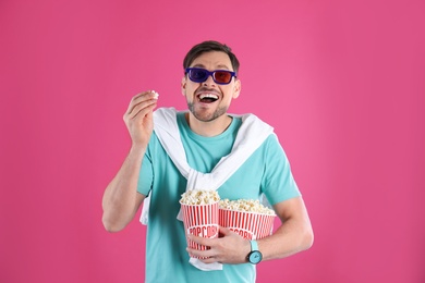 Man with 3D glasses and tasty popcorn on color background