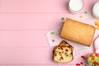 Photo of Delicious cake with candied fruits and milk on pink wooden table, flat lay. Space for text