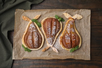 Delicious pears baked in puff pastry with powdered sugar and mint on wooden table, top view