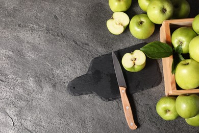 Photo of Ripe green apples, cutting board and knife on grey table, flat lay. Space for text