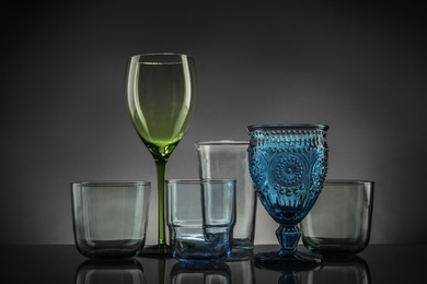 Photo of Set of different colorful empty glasses on table against grey background