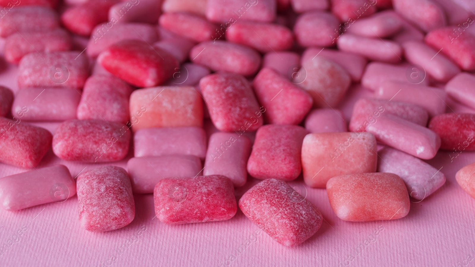 Photo of Many sweet chewing gums on pink background, closeup