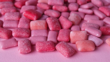 Photo of Many sweet chewing gums on pink background, closeup