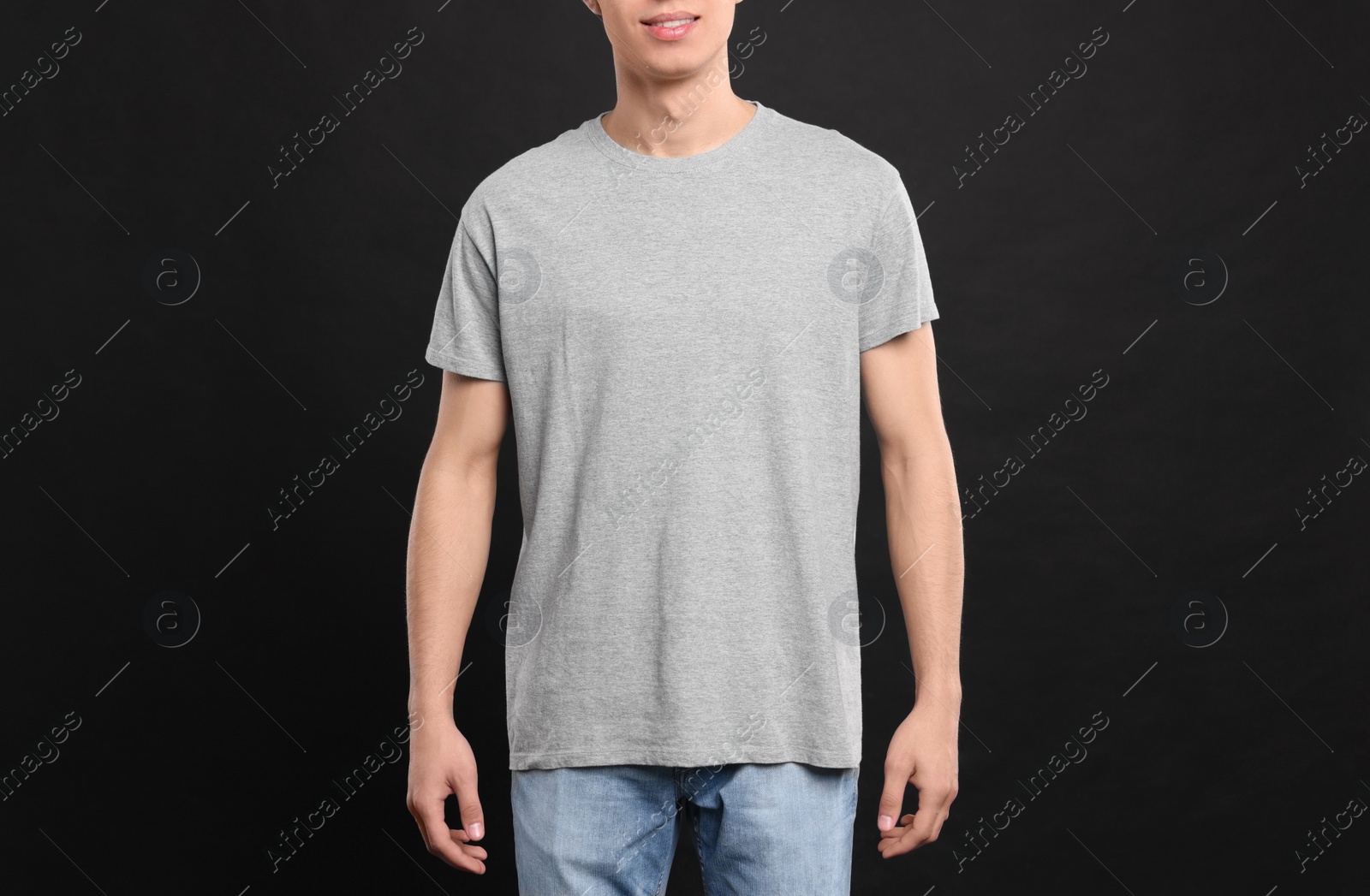 Photo of Man wearing light gray t-shirt on black background, closeup. Mockup for design